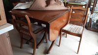 Overall view of the wooden drop leaf table with leaves lowered and four matching chairs