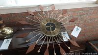 Front view of starburst clock on surface against brick background