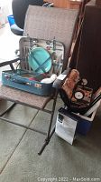 Patio rocker chair holding blue picnic set suitcase with utensils and plates inside