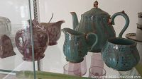 Turquoise Sadler teapot, sugar bowl and cream pitcher with cranberry floral pattern set and Royal Winton salt and pepper shakers visible on shelf.