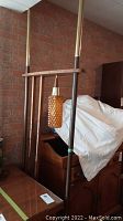 Floor-to-ceiling lamp frame with hanging amber textured glass shade and wood accents