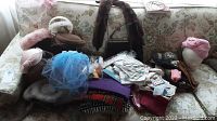Wide view of the vintage ladies accessories including hats, scarves, fur stoles, and gloves arranged on couch and chair.