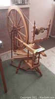 Full view of the wood spinning wheel showing the large wheel and support structure.