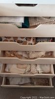 Five drawers filled with assorted vintage table linens, showing various textures and colors of fabric.
