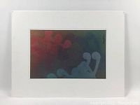 Frontal view of the matted monoprint showing muted abstract shapes in red, blue, and green on dark background, signed lower right.