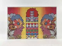 Full view of colorful lithograph with two psychedelic floral heads facing inward with geometric patterned section in the center on a yellow to red gradient background, shrink-wrapped on foam board.