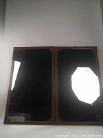 Full view of two large wood framed mirrors side by side, showing the reflective surfaces and overall shape