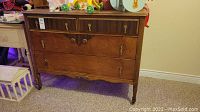 Full front view of the antique wooden dresser showing four drawers and castor feet.