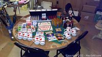 Wide view of the poker table set up with cards, chips, mugs, coasters, and chairs around it