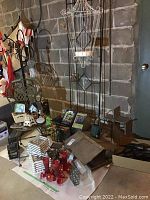 Overall view of metal chair, bird feeders on a table, wooden birdhouses, and trellis against concrete block wall