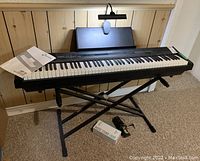 Digital piano on X-style stand with sustain pedal and clamp-on light mounted on music rest