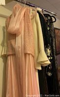 Photo showing various ladies evening wear pieces including peach sequin top and skirt, cream wool suit, and black beaded tops hanging on rack