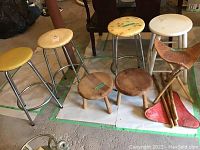 Overall shot of all eight stools including metal frame stools, small wooden stools, and Mexican leather stools.