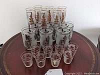 Full set arranged with tall gold decorated tumblers in back, medium platinum decorated tumblers in middle, and small gold decorated shot glasses up front