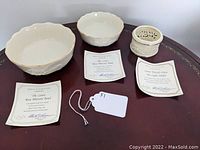 Three Lenox porcelain pieces on a wooden surface with certificates of authenticity displayed.