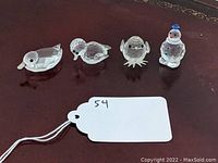 Overview of all four figurines on a wooden surface with a white tag labeled 54