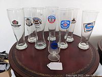 Eight German logo beer glasses arranged on a table showing overall lot contents and shape of the glasses
