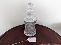 Full view of clear glass liquor decanter with stopper showing detailed cut glass pattern on the body.