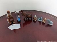 Group of 7 assorted figurines arranged on a wooden surface in a line, showing each distinct item in the lot