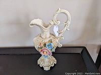 Full view of the large ornate Capodimonte ewer showing its overall shape, handle, and flower decoration on the front.
