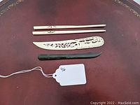 Full view of both pairs of chopsticks and letter openers on a reddish-brown surface with a small tag labeled 46