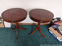 Front view of the pair of mahogany drum tables with leather inlaid tops and tripod bases, showing overall condition and design.