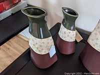 Pair of modern design ceramic vases placed on black surface, showing the varying sizes and tri-color scheme.