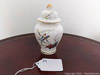 Front view of porcelain ginger jar showing birds and cherry blossoms artwork with gold accents.
