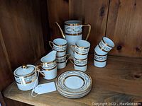 Full set including coffee pot, creamer, sugar bowl, 6 cups stacked and on shelf, 5 saucers stacked.