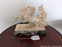 Full view of the vintage Roman charioteer sculpture with two horses on a marble base.