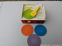 View of the music box record player with four colored discs, showing condition and all parts included