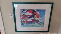 Full view of the framed pastel artwork depicting a winter scene with a red house and snowy trees, showing the overall condition and presentation in the green frame.