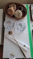 Photo showing two clear bubble-style glass candle holders, two white taper candles, and brass candle snuffer laid out on a white surface.