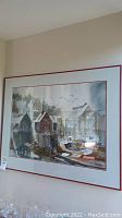 Full view of framed watercolor painting showing harbor scene with dockhouses and boats