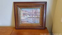 Front view of framed oil painting showing winter landscape with barn and trees