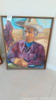 Full view of framed oil painting showing seated cowboy wearing a hat and horse silhouette