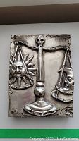 Front view showing the full tile with sun and moon on the balance scale under antique silver finish.
