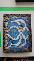 Photo showing full view of rectangular ceramic art tile with blue and white floral design and distressed finish.