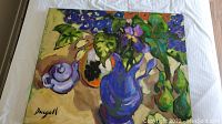 Full view of the oil painting laid on a white cloth, showing overall composition of flowers, vase, fruit and teapot.