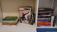 Books arranged on shelves including Marvel Comics poster collection and various reference books