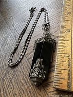 Photo showing full length of pendant and chain next to ruler for size reference.