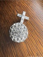 Close-up photo of the rhinestone crucifix brooch placed on a wooden surface