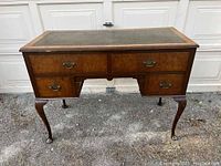 Front angled view of French Provincial desk showing wood grain, drawer handles, and cabriole legs.