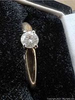 Top-down view of ring in box showing solitaire diamond and band