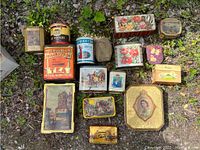 Top-down view of all 17 tins showing size and design variety laid on ground outdoors.