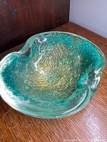 Turquoise and green Murano glass ashtray or dish showing the textured gold-accented interior and clear glass edges.