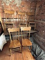 Five rare pressed back chairs with carved fish motif on backs, turned and twisted spindles and legs, set on wood floor against brick wall.