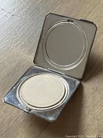 Open compact showing the mirror and powder puff compartment.