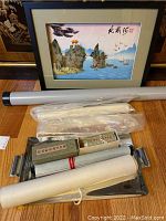 Framed signed Asian art print along with seven wrapped Asian scroll art pieces on a tray
