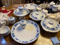 Overview of 25-piece set on table showing casseroles, platter, compote, mugs, lidded jars and bowls.